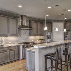 a large kitchen with an island and lots of counter space, along with bar stools