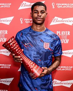 a young man holding a soccer ball in his right hand and wearing a blue shirt