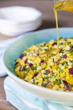 corn salad in a bowl with dressing being poured on top