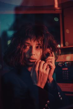 a woman talking on a cell phone while standing in front of a microwave and window