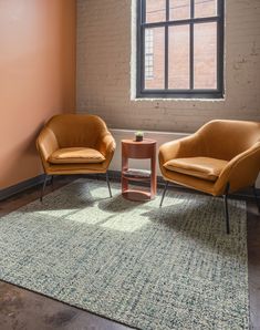 two chairs and a table in front of a brick wall with a large window on the other side