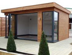 a small wooden building sitting on top of a wooden deck next to trees and bushes