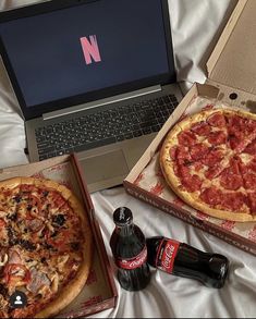 two pizzas, one with pepperoni and the other with mushrooms are sitting in front of a laptop