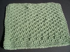 a green crocheted dishcloth sitting on top of a black table next to a pair of scissors