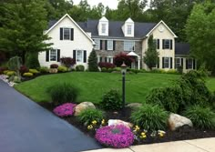 a large house with landscaping around it and flowers in the front yard on either side