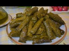 there is a plate full of stuffed grape leaves on the table next to a bowl of olive oil