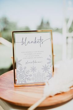 a wooden table topped with a sign and a feather on top of it's stand