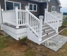 a white porch with steps and railings in front of a gray house on a cloudy day