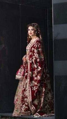 a woman in a red and gold bridal gown is posing for the camera with her hand on her hip