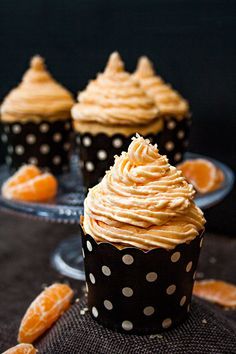 cupcakes with frosting and orange slices on a table