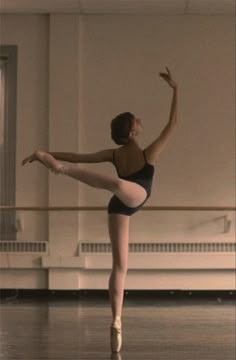 a ballerina in a black leotard is practicing her moves