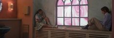 two people sitting on a window sill in front of a large stained glass window