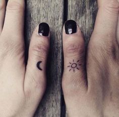 two people with matching tattoos on their fingers, one has a sun and the other has a moon