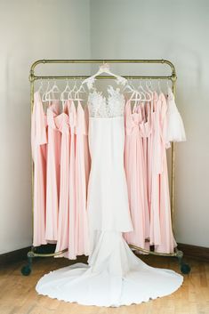 a wedding dress hanging on a rack in front of other dresses