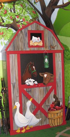 a painted barn with farm animals on the door and in front of it is a basket full of apples