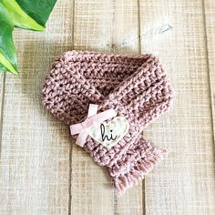 a crocheted hat with a name on it and a pink bow around the neck