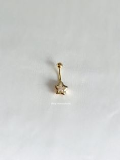 a small gold nose piercing with a star on the end, sitting on a white surface