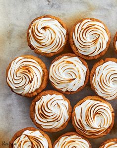 there are many small desserts with white frosting on the top one is round