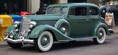 an old green car is parked on the street