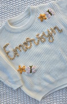 a white sweater with flowers on it that says grandma written in gold thread and sequins