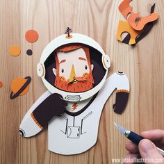 a paper cut out of a man wearing a space suit and holding a pair of scissors