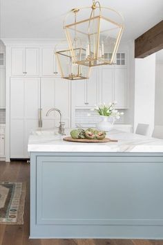 a kitchen with white cabinets and a gold chandelier hanging from the center island