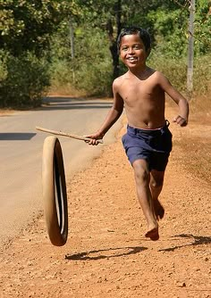 a young boy is running with a large object in his hand on the side of the road