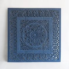 an intricately carved blue tile is mounted on the wall in front of a white wall