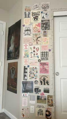 a wall covered in posters and pictures next to a white door with an open doorway