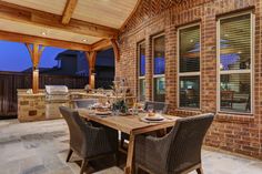 an outdoor kitchen and dining area with brick walls