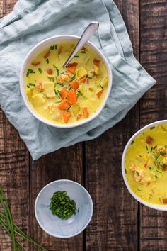 two bowls filled with soup on top of a wooden table