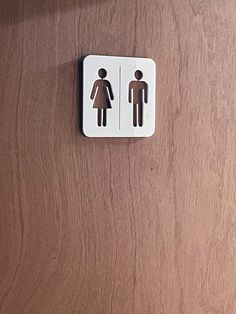 a wooden door with two restroom signs on the front and back of it, one showing a man and woman's silhouette