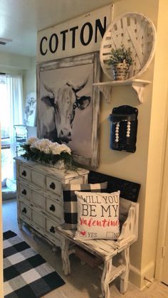 a living room with an old dresser and cow pictures on the wall above it, along with other decor