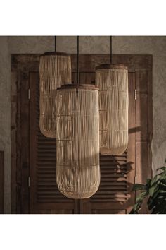 three lights hanging from the ceiling in front of a wooden door and window with shutters