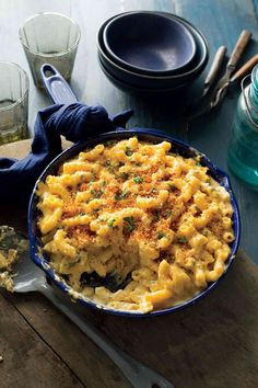 macaroni and cheese in a blue dish on a wooden table with utensils