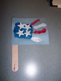 an american flag made out of popsicle sticks on a table with blue paper and white stars