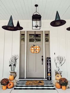 a front porch decorated for halloween with pumpkins and witch hats hanging from the ceiling