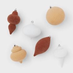 four different ornaments are shown in the shape of seashells, one is orange and one is white