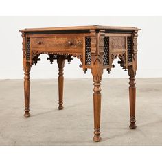 an antique wooden desk with drawers and carved carvings on the top, sitting on concrete flooring