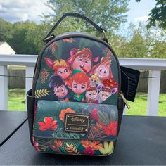 the back side of a backpack with disney's characters painted on it and trees in the background