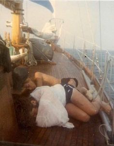 two people laying on the deck of a boat