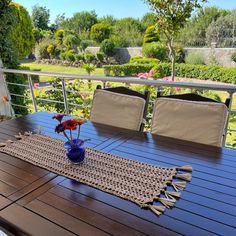 the table is set on the deck with flowers in a vase and placemats