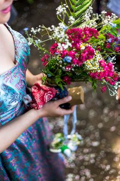 a woman in a blue dress holding a bouquet of pink and white flowers on her left hand