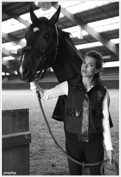 a woman standing next to a brown horse