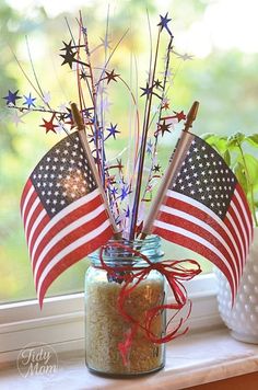 an american flag in a mason jar on a window sill next to a potted plant