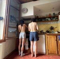 two people are standing in the kitchen looking out the window