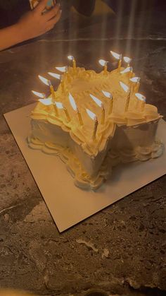 a birthday cake with lit candles sitting on top of a piece of paper that has been cut in half