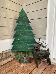 a wooden christmas tree sitting on top of a wooden floor next to a potted plant