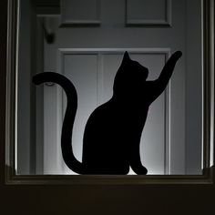 a black cat sitting on top of a window sill in front of a door