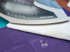 an iron is sitting on top of a purple and blue blanket next to a white towel